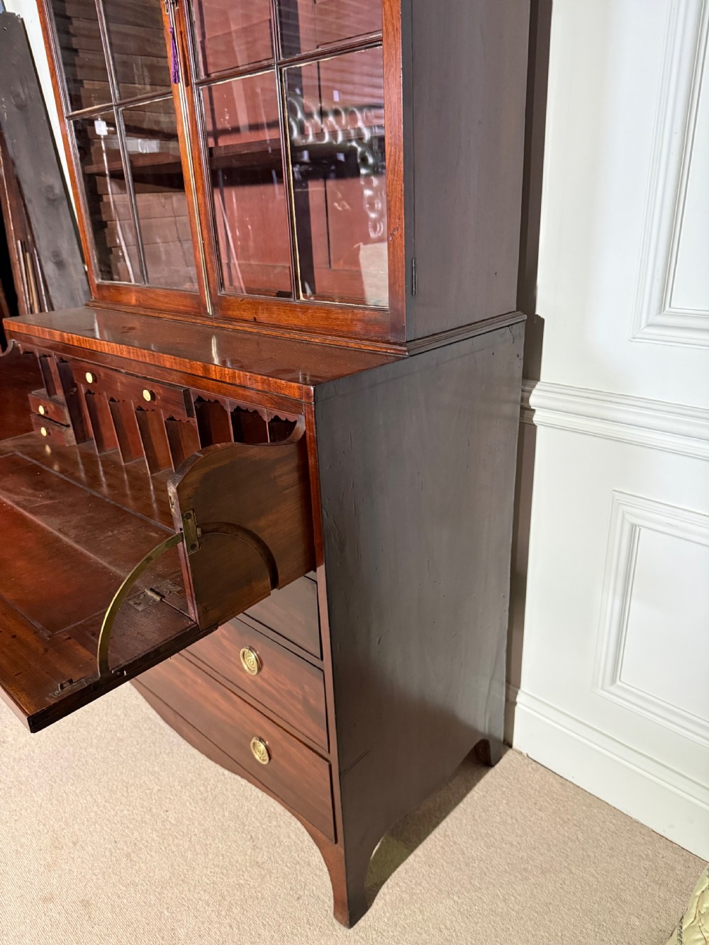 A tall Georgian mahogany secretaire bookcase featuring upper glazed doors with gothic arch bars, an arched pediment with finials, and a lower chest of drawers with brass ring handles. View XI