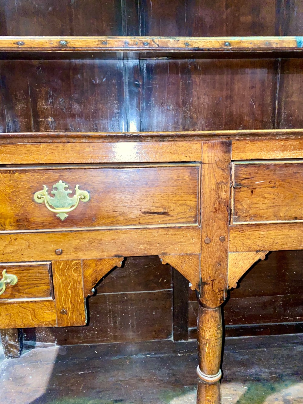 A Georgian oak dresser featuring a tall open plate rack top above five base drawers, turned legs, brass handles, and a lower pot board. View IV