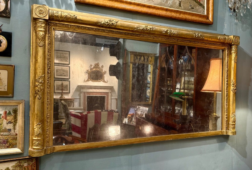 A large rectangular Regency giltwood overmantel mirror featuring architectural fluted pilasters, corner rosettes, and floral moulding along the top frame. View III