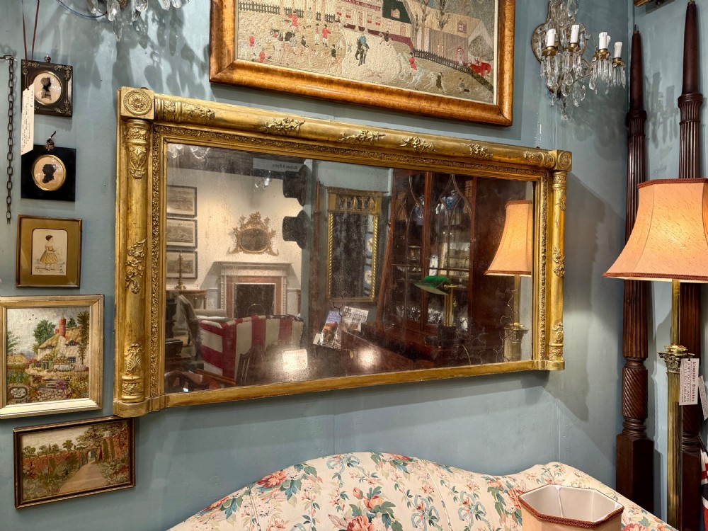 A large rectangular Regency giltwood overmantel mirror featuring architectural fluted pilasters, corner rosettes, and floral moulding along the top frame. View V