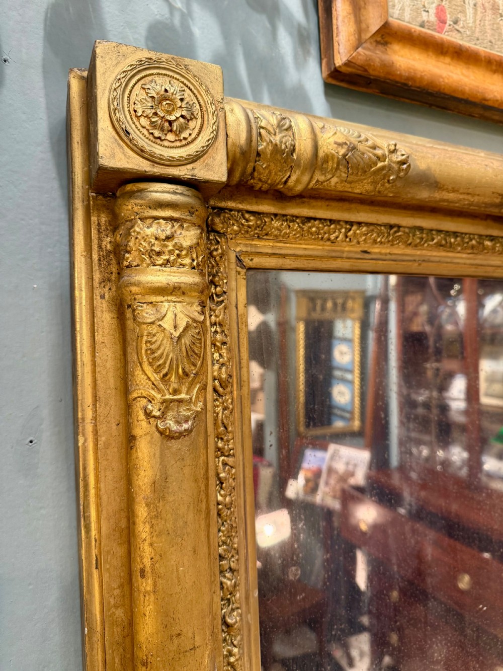 A large rectangular Regency giltwood overmantel mirror featuring architectural fluted pilasters, corner rosettes, and floral moulding along the top frame. View VI