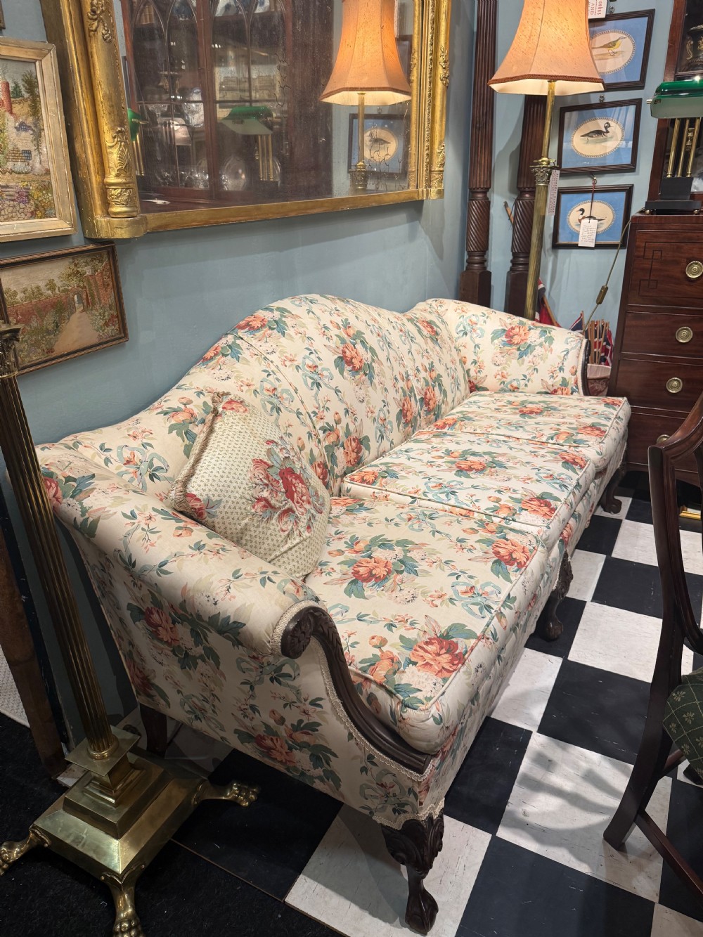 A nineteenth-century Chippendale style camel back sofa with floral chintz upholstery and carved mahogany legs.