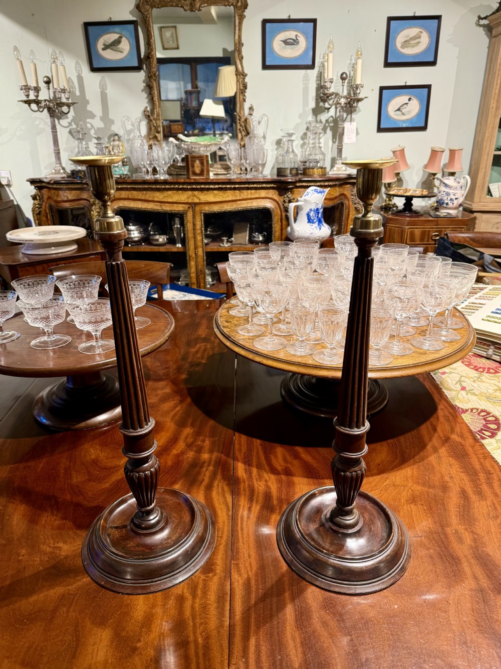 A pair of tall George III style turned mahogany candlesticks with fluted columns, circular moulded bases, and brass sconces.