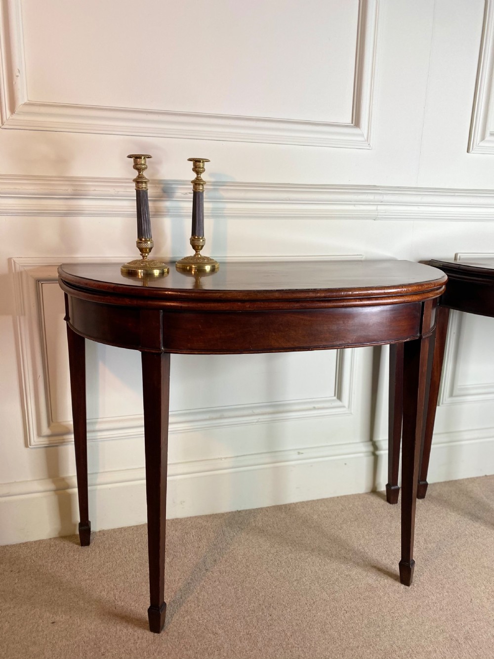 A pair of late eighteenth-century Georgian mahogany demilune card tables with fold-over tops and square tapered legs. View II
