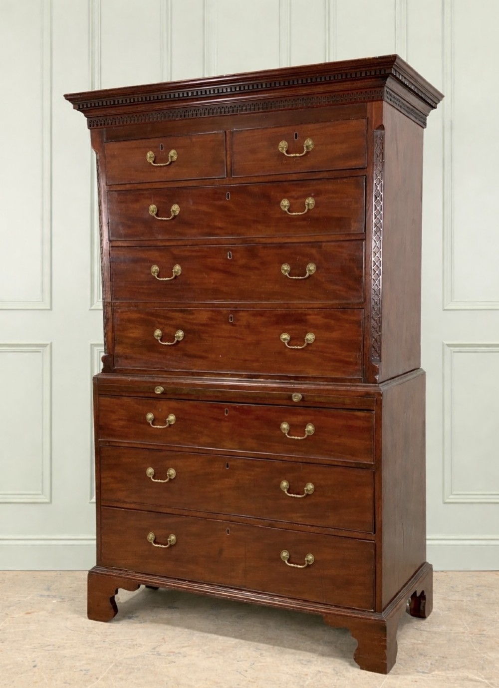 An 18th-century George III mahogany chest on chest featuring two stacked drawer sections, a brushing slide, dentil moulding, blind fretwork, and bracket feet.
