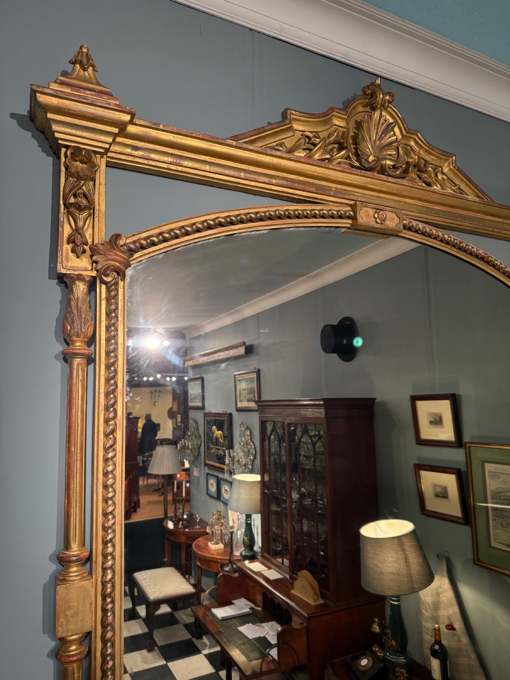 A 19th-century giltwood overmantel mirror featuring an arched top, detailed shell cresting, and carved side pilasters. View III