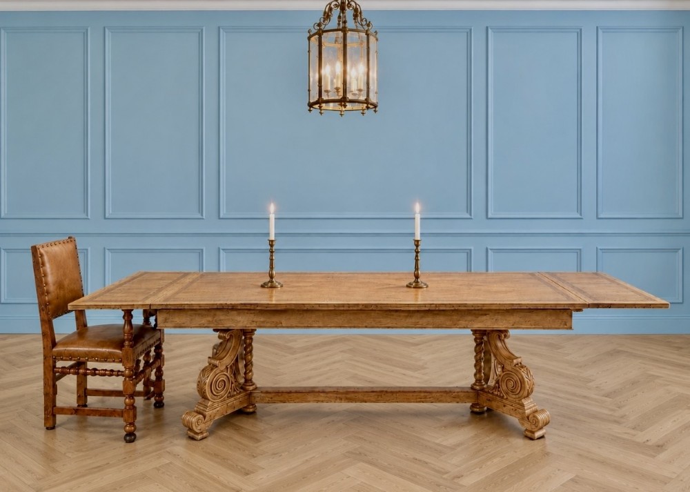 A large carved oak refectory dining table featuring extended draw-leaf ends and carved architectural trestle legs connected by a central stretcher.