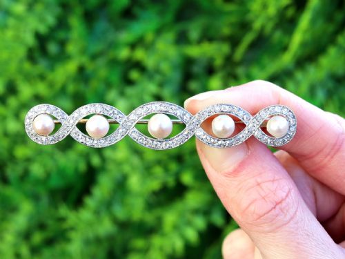 fig 1. An Art Deco gold bar brooch featuring five natural pearls framed within a diamond-set intertwined ribbon setting.