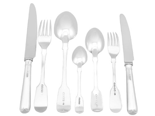 fig 3. An antique Victorian sterling silver cutlery set in the Fiddle pattern, featuring knives, forks, spoons, and ladles arranged on a plain white background.