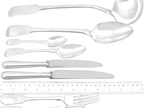 fig 5. An antique Victorian sterling silver cutlery set in the Fiddle pattern, featuring knives, forks, spoons, and ladles arranged on a plain white background.