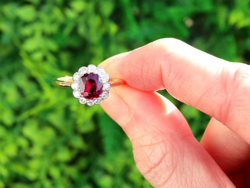 fig 1. An 18ct yellow gold cluster ring featuring a central cushion cut red ruby framed by a halo of round diamonds.
