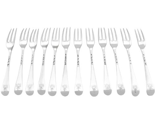 fig 1. A set of twelve antique sterling silver table forks featuring three tines and smooth Hanoverian pattern handles arranged side by side.