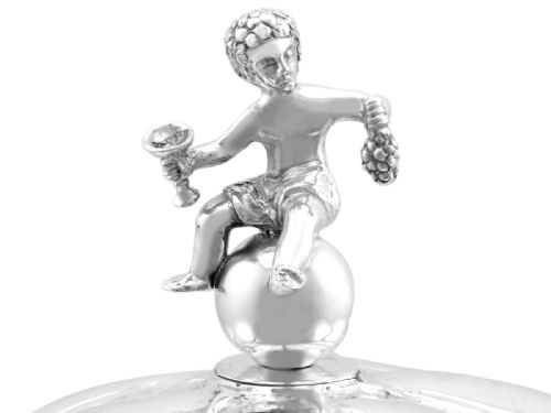 fig 6. An antique German sterling silver covered presentation cup featuring chased relief panels, set cabochon gemstones, and a putto finial.