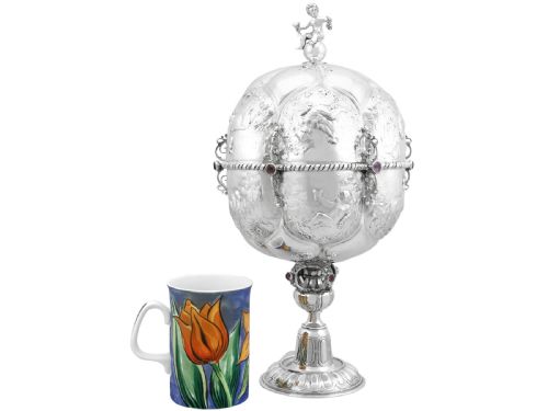 fig 4. An antique German sterling silver covered presentation cup featuring chased relief panels, set cabochon gemstones, and a putto finial.