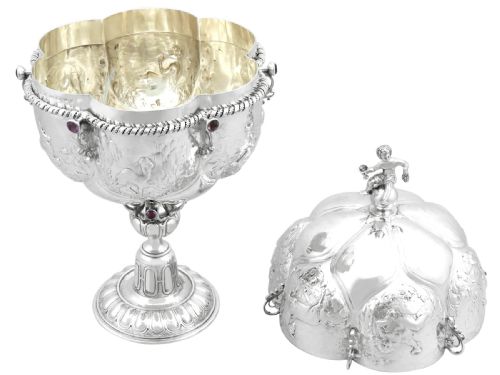 fig 5. An antique German sterling silver covered presentation cup featuring chased relief panels, set cabochon gemstones, and a putto finial.