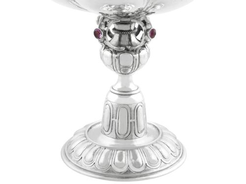 fig 7. An antique German sterling silver covered presentation cup featuring chased relief panels, set cabochon gemstones, and a putto finial.