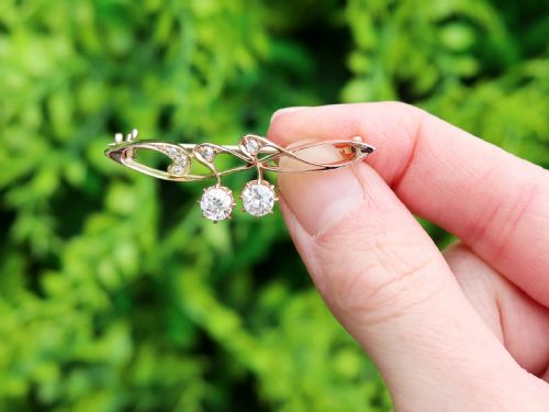 fig 1. An antique 14ct yellow gold Art Nouveau bar brooch featuring openwork whiplash curves set with accent diamonds and two suspended claw-set diamonds.