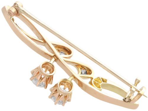 fig 4. An antique 14ct yellow gold Art Nouveau bar brooch featuring openwork whiplash curves set with accent diamonds and two suspended claw-set diamonds.