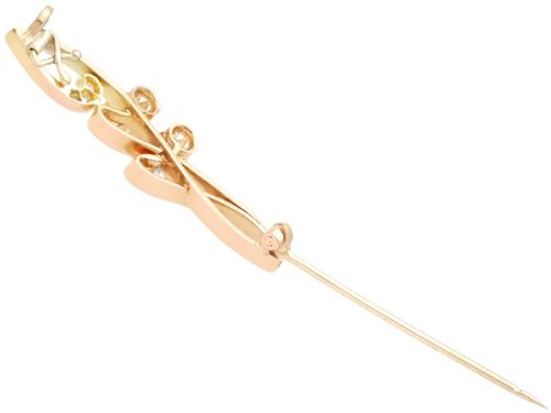 fig 5. An antique 14ct yellow gold Art Nouveau bar brooch featuring openwork whiplash curves set with accent diamonds and two suspended claw-set diamonds.