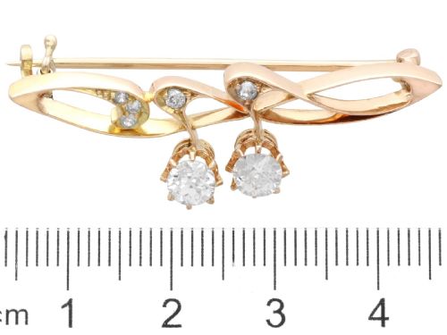 fig 6. An antique 14ct yellow gold Art Nouveau bar brooch featuring openwork whiplash curves set with accent diamonds and two suspended claw-set diamonds.