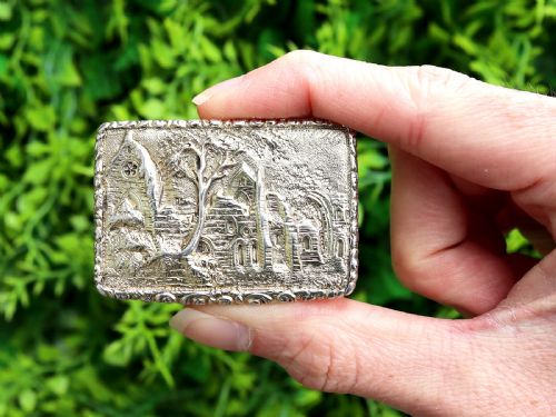 fig 2. A rectangular sterling silver gilt vinaigrette featuring an embossed scene of architectural ruins surrounded by a scrolling border.