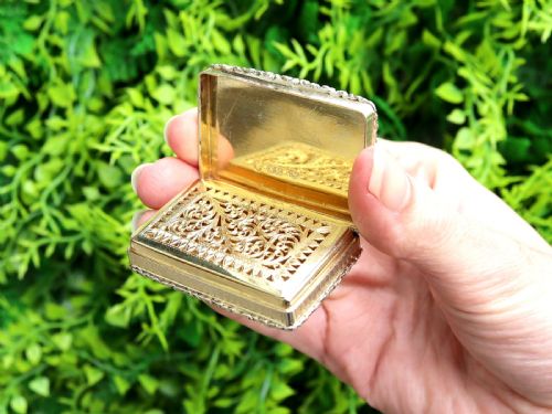 fig 3. A rectangular sterling silver gilt vinaigrette featuring an embossed scene of architectural ruins surrounded by a scrolling border.