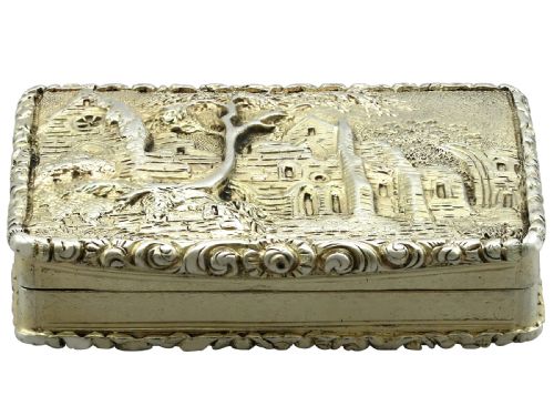 fig 4. A rectangular sterling silver gilt vinaigrette featuring an embossed scene of architectural ruins surrounded by a scrolling border.