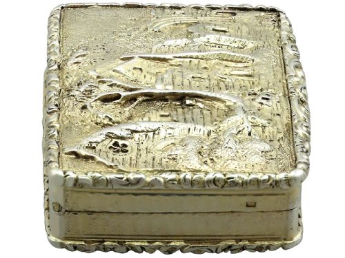 fig 5. A rectangular sterling silver gilt vinaigrette featuring an embossed scene of architectural ruins surrounded by a scrolling border.