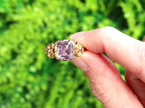 fig 1. An antique 15ct yellow gold ring featuring an emerald-cut purple amethyst gemstone with detailed scrollwork on the shoulders.
