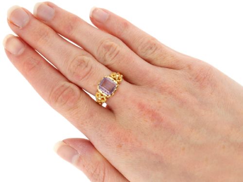 fig 6. An antique 15ct yellow gold ring featuring an emerald-cut purple amethyst gemstone with detailed scrollwork on the shoulders.