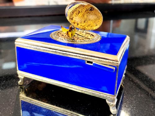 fig 1. A rectangular cobalt blue guilloche enamel and silver-gilt singing bird box with an engraved oval hatch cover and tiny cabriole feet.