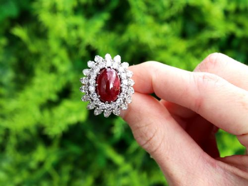 fig 1. A vintage 18ct yellow gold ring featuring a central oval cabochon red ruby surrounded by a double tiered cluster halo of diamonds.
