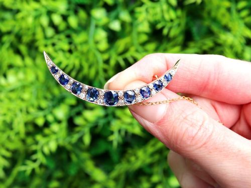 fig 1. A crescent moon brooch set with graduated blue sapphires and accent diamonds in nine-carat yellow gold with an attached safety chain.