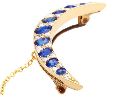 fig 2. A crescent moon brooch set with graduated blue sapphires and accent diamonds in nine-carat yellow gold with an attached safety chain.