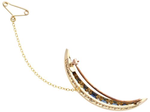 fig 4. A crescent moon brooch set with graduated blue sapphires and accent diamonds in nine-carat yellow gold with an attached safety chain.