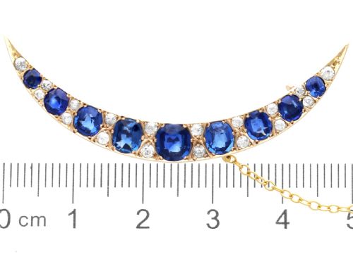 fig 6. A crescent moon brooch set with graduated blue sapphires and accent diamonds in nine-carat yellow gold with an attached safety chain.