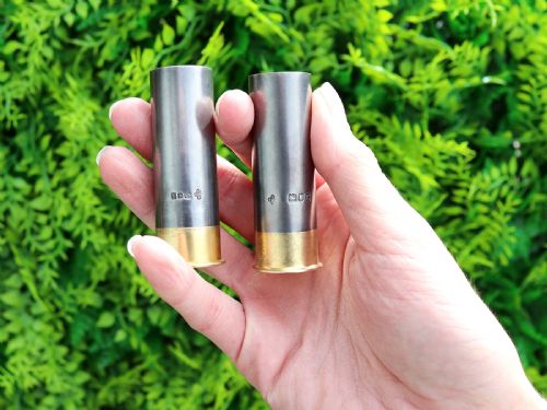fig 1. A pair of Edwardian sterling silver pepper shakers shaped like shotgun cartridges with dark silver bodies and gilt metal bases.
