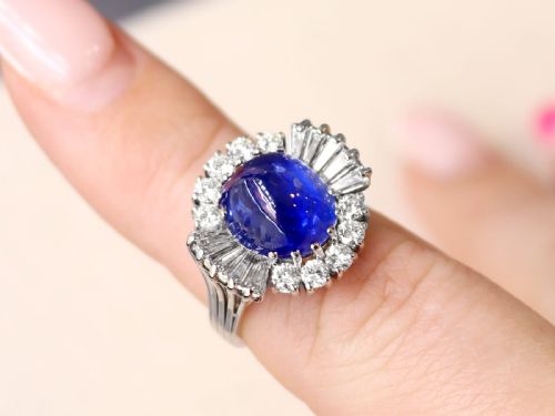 fig 2. A vintage 18ct white gold cluster ring featuring a central oval cabochon blue sapphire framed by brilliant-cut and baguette-cut diamonds.