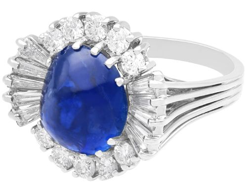 fig 4. A vintage 18ct white gold cluster ring featuring a central oval cabochon blue sapphire framed by brilliant-cut and baguette-cut diamonds.