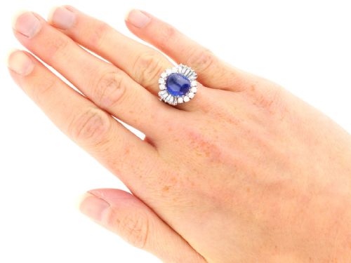 fig 8. A vintage 18ct white gold cluster ring featuring a central oval cabochon blue sapphire framed by brilliant-cut and baguette-cut diamonds.