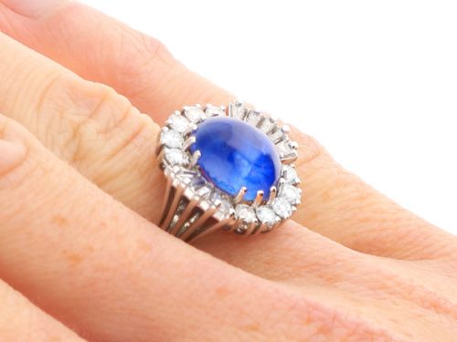 fig 9. A vintage 18ct white gold cluster ring featuring a central oval cabochon blue sapphire framed by brilliant-cut and baguette-cut diamonds.