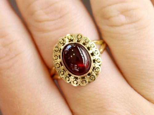 fig 2. A vintage 18ct yellow gold dress ring set with a central oval cabochon garnet encircled by an openwork gold pattern border.