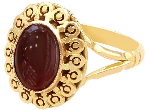 fig 3. A vintage 18ct yellow gold dress ring set with a central oval cabochon garnet encircled by an openwork gold pattern border.