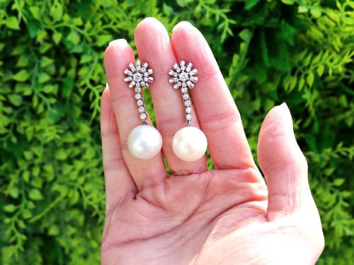 fig 1. A pair of 18ct white gold drop earrings featuring round South Sea pearls suspended from articulated diamond stems and floral cluster stud tops.