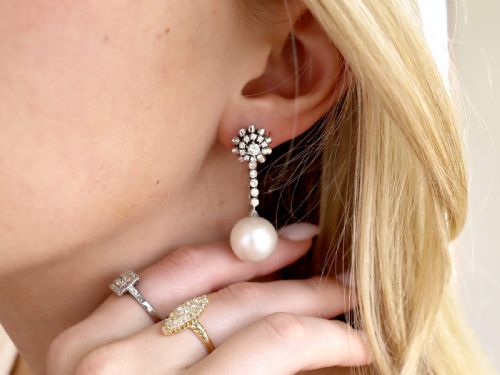 fig 3. A pair of 18ct white gold drop earrings featuring round South Sea pearls suspended from articulated diamond stems and floral cluster stud tops.