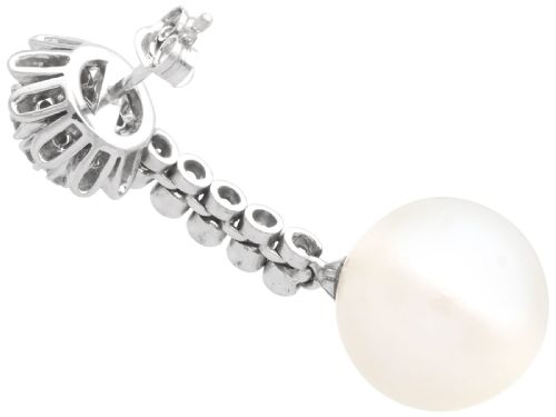 fig 6. A pair of 18ct white gold drop earrings featuring round South Sea pearls suspended from articulated diamond stems and floral cluster stud tops.