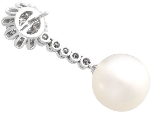fig 7. A pair of 18ct white gold drop earrings featuring round South Sea pearls suspended from articulated diamond stems and floral cluster stud tops.