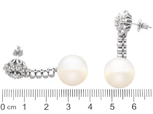 fig 8. A pair of 18ct white gold drop earrings featuring round South Sea pearls suspended from articulated diamond stems and floral cluster stud tops.