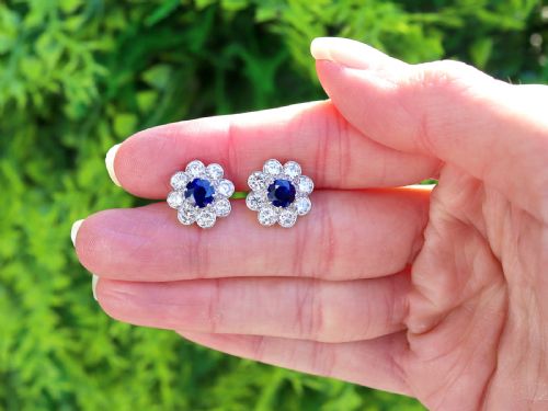 fig 1. A pair of antique floral-shaped cluster earrings featuring central round blue sapphires encircled by bright diamonds.