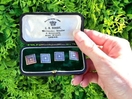 fig 1. A set of four square 18ct yellow gold cufflinks decorated with blue enamel geometric patterns, presented inside a fitted black box.